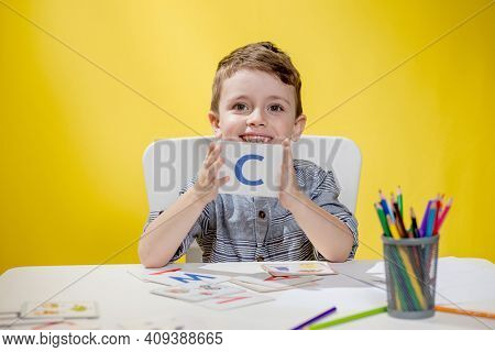 Happy Smiling Little Preschool Boy Shows Letters At Home Making Homework At The Morning Before The S
