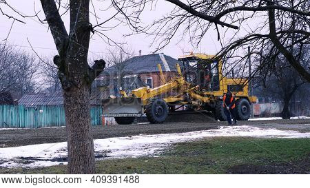 Maikop, Republic Of Adygea, Russia - January 16, 2021: A Yellow Grader With A Raised Scraper Drives 