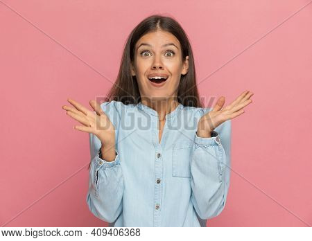 young casual woman feeling happily surprised against pink studio background