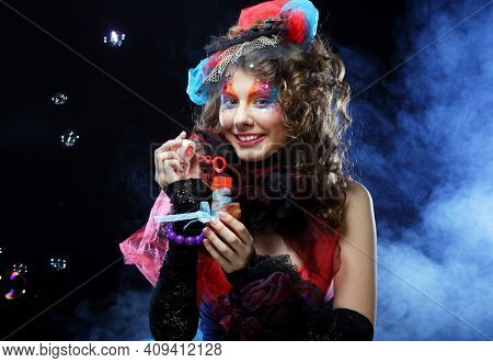 Fashion female model with creative make-up and curly hair blowing soap bubbles. Doll style.