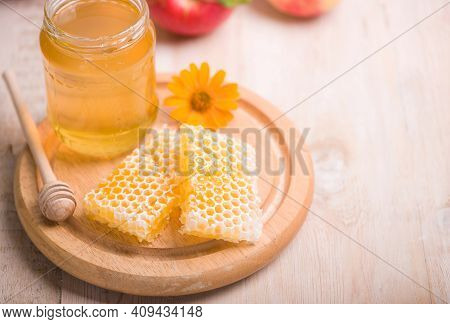 Honey Dipper On The Bee Honeycomb Background. Honey Tidbit In Glass Jar And Honeycombs.
