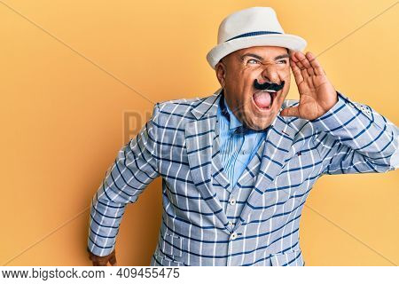 Mature middle east man with mustache wearing vintage and elegant fashion style shouting and screaming loud to side with hand on mouth. communication concept. 