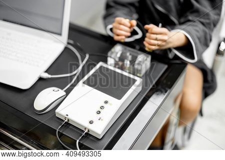 Woman Takes Hold Of The Brass Handpieces Of Bioenergetic Testing Device