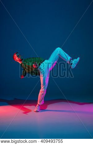 Modern. Stylish Sportive Boy Dancing Hip-hop In Stylish Clothes On Colorful Background At Dance Hall