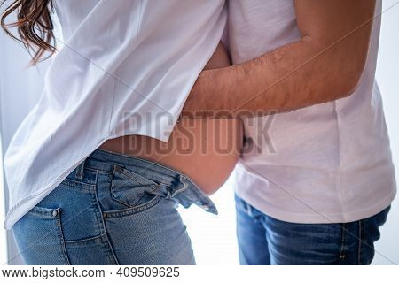 Pregnant Woman With A Man. Family Pregnant Couple. Man Hugs A Pregnant Woman Over Belly. Future Pare