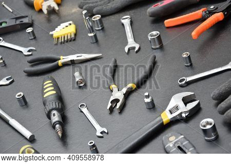 Handyman Tool Kit On Black Wooden Table. Many Wrenches And Screwdrivers, Pilers And Other Tools For 