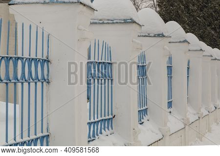 The Fence Consists Of Stone Pillars With Metal Sections
