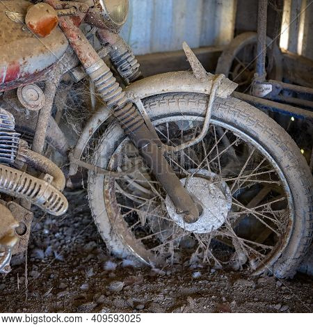 Closeup Of The Front Wheel Of A Rusted Vintage Motorcycle Covered In Dirt And Cobwebs