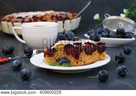 Piece Of Cake With Blackthorns Berries And Cup Of Coffee On Dark Background