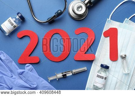 Flat Lay Composition With Coronavirus Vaccine And Number 2021 On Blue Background