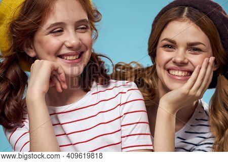 Happy Sisters Having Fun On A Blue Background And Hats On Their Heads