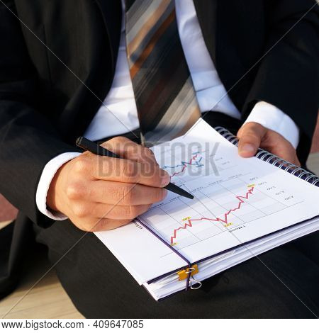 Businessman Evaluates Company Data And Checks Charts And Values