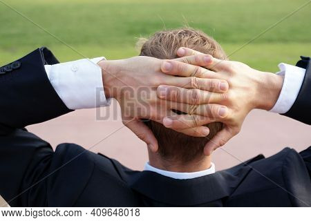 Businessman Sits Relaxed His Hands Behind His Head On Park Bench In City Park