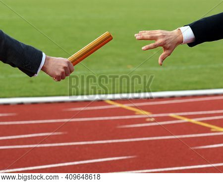 Businessmen Pass On The Baton In Relay Race In Stadium