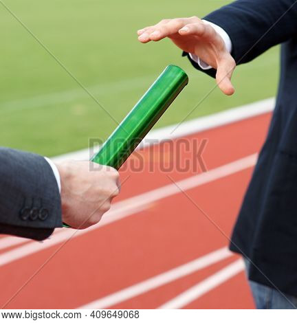 Businessmen Pass On The Baton In Relay Race In Stadium