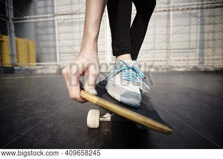 Close-up Shot Of Feet Of A Young Asian Woman Skateboarding Outdoors