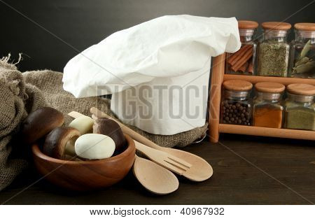 Sammansättning med kockens hatt och kitchenwear på bordet på grå bakgrund