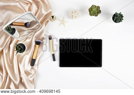 Top View To Digital Tablet Computer, Mirrow And Make Up Brushes On White Desk. Makeup Cosmetic, Onli