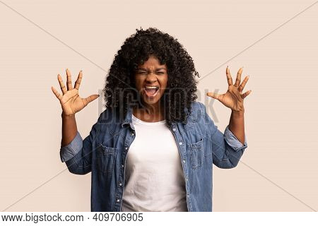 Furious Young Black Woman Raising Hands Up And Screaming, Showing Her Negative Emotions Over Grey St