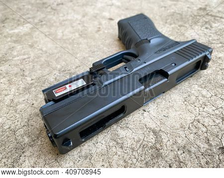 Bangkok Thailand - 21 February 2021: Air Soft Gun Glock 18C Pistol Gun With Laser Sight On The Floor