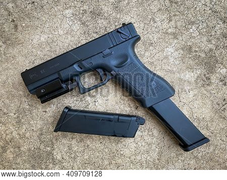 Bangkok Thailand - 21 February 2021: Air Soft Gun Glock 18c Pistol Gun With Laser Sight On The Floor
