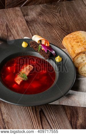 Ukrainian Traditional Borshch. Beetroot And Cabbage Soup With Meat. Close-up Of The Dish In Black Pl