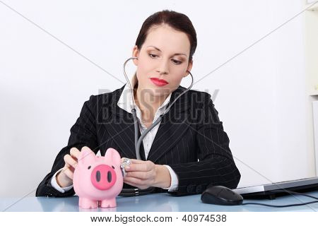 Atraktivní podnikatelka kontrola prasátko s sthetoscope. Finanční analýza konceptu.