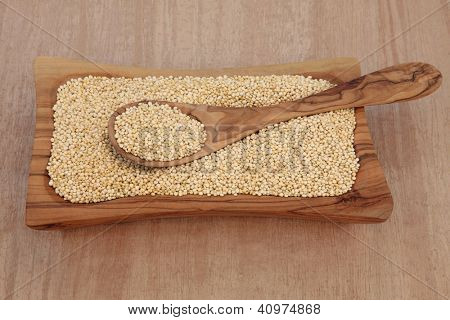 Quinoa Tahıl bir zeytin ahşap kase ve kaşık papirüs arka plan üzerinde.