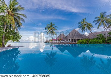 Summer Vacation At A Luxury Resort With Infinity Pool With Amazing Green Palm Trees Under Blue Sky. 