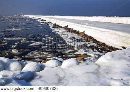 Icy Road To The Lighthouse On Mangalsala Pier In Baltic Sea Located At Riga Sea Port, Latvia, Europe