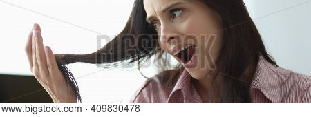 Woman Holds Comb In Her Hand And Looks At Her Hair In Panic. Hair Loss In Women Concept