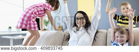 Woman, Boy And Two Girls Are Sitting On Couch And Laughing Happily And Raising Their Hands Up. Priva