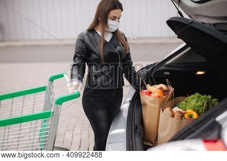 Groceries In Females Hand By The Car Truck. Woman In Protective Mask And Disposable Gloves. Fresh Fr