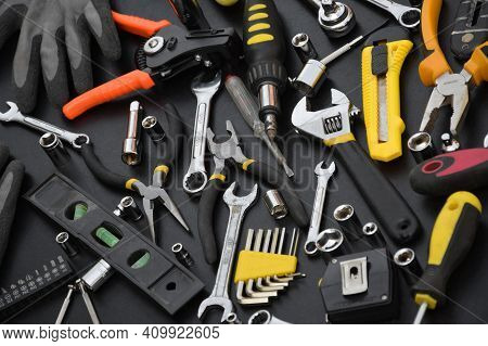 Handyman Tool Kit On Black Wooden Table. Many Wrenches And Screwdrivers, Pilers And Other Tools For 
