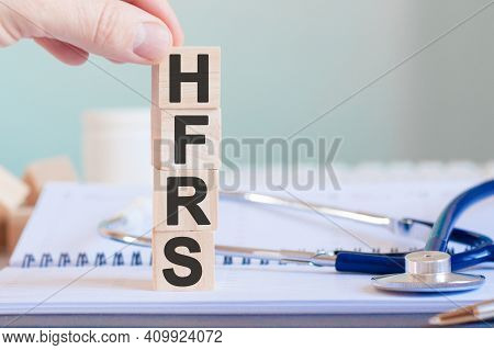 The Word Hfrs Is Written On Wooden Cubes Near A Stethoscope On A Paper Background. Hfrs - Short For 
