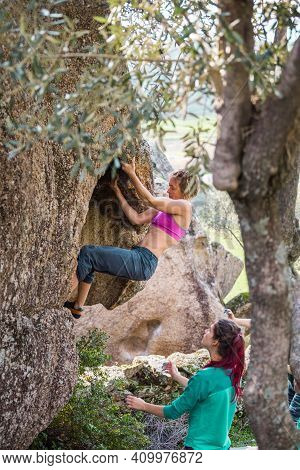 Friends Go In For Sports In Nature, Bouldering On Rocks, Girl Climbs A Big Stone, Woman Is Belayng P