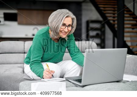 Well-dressed Gray Haired Woman On Retirement Managing Family Budget At Home, With Glasses, Watching 