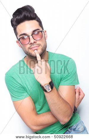 young casual man holding his middle finger on his chin while looking into the camera. on white background