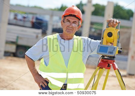 Portrait of builder worker with theodolite transit equipment at construction site outdoors during surveyor work