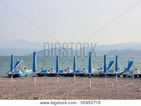 Water Cycles And Parasols At Empty Beach In The Morning
