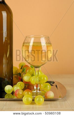 White wine in glass with bottle on salver on beige background