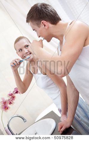 Married couple brushes teeth in bathroom