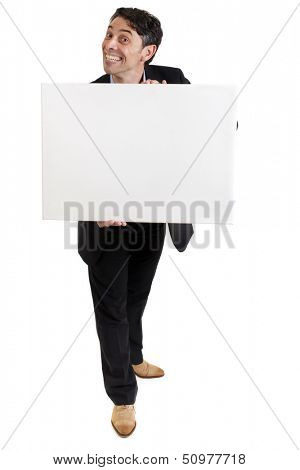 Smart, middle-aged businessman with a cheesy insincere toothy grin holding a blank white sign in his hands with copyspace for your text or advertisement, isolated on white