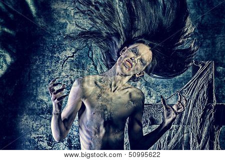 Portrait of a bloodthirsty vampire at the night cemetery. Halloween.