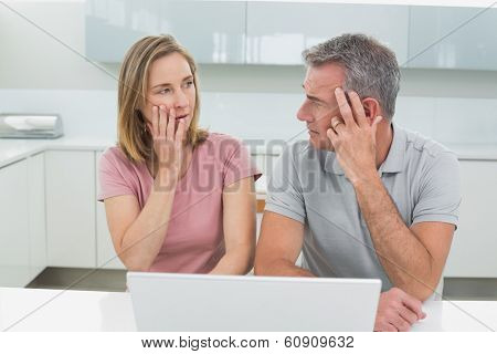 Shocked couple using laptop in the kitchen at home