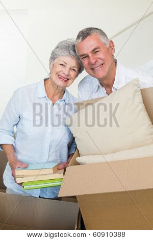 Happy senior couple moving into new home smiling at camera