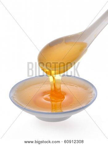 syrup pouring on spoon on white background