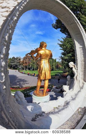Dynamic sculptural portrait of the King of Waltz - Johann Strauss. Elegant bronze statue with violin shines in the bright summer sun