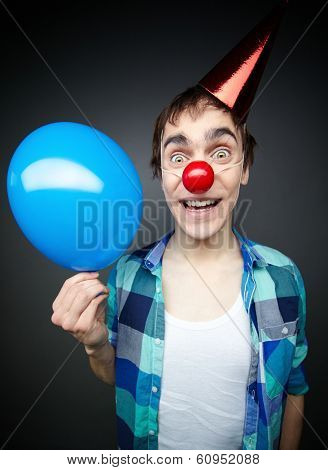 Happy guy holding a balloon and smiling crazily at camera celebrating foolÃ?ÃÂ¢??s day
