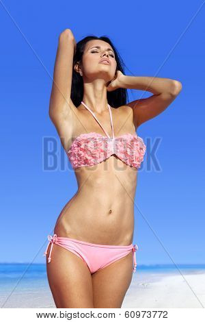 beautiful woman sunbathing in pink bathing suit on beach